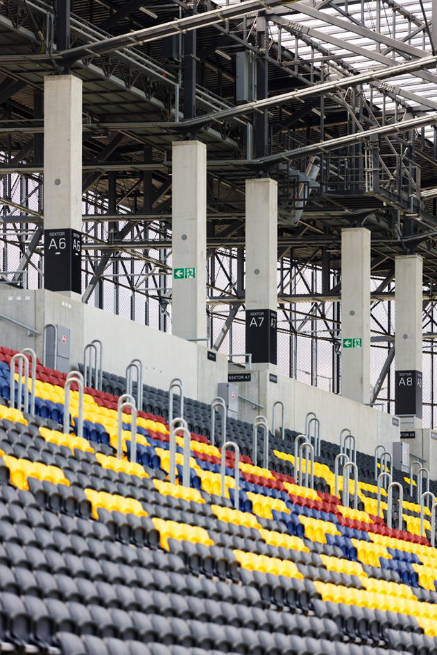Fragment trybun z żółtymi, niebieskimi i czerwonymi siedziskami na Stadionie Pogoni w Szczecinie